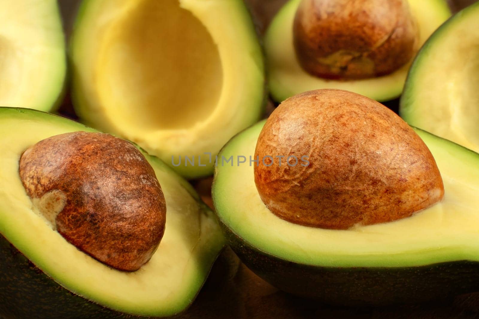 Closeup detail - heap  of avocados cut in half, with brown seeds.