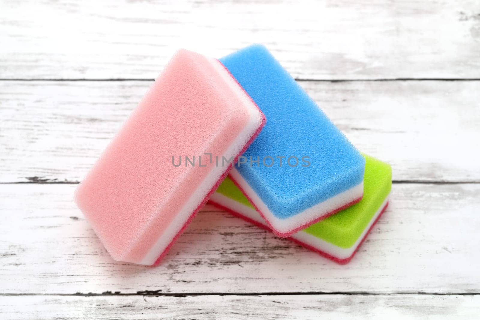 color rectangular sponges for washing dishes and cleaning on white wooden background