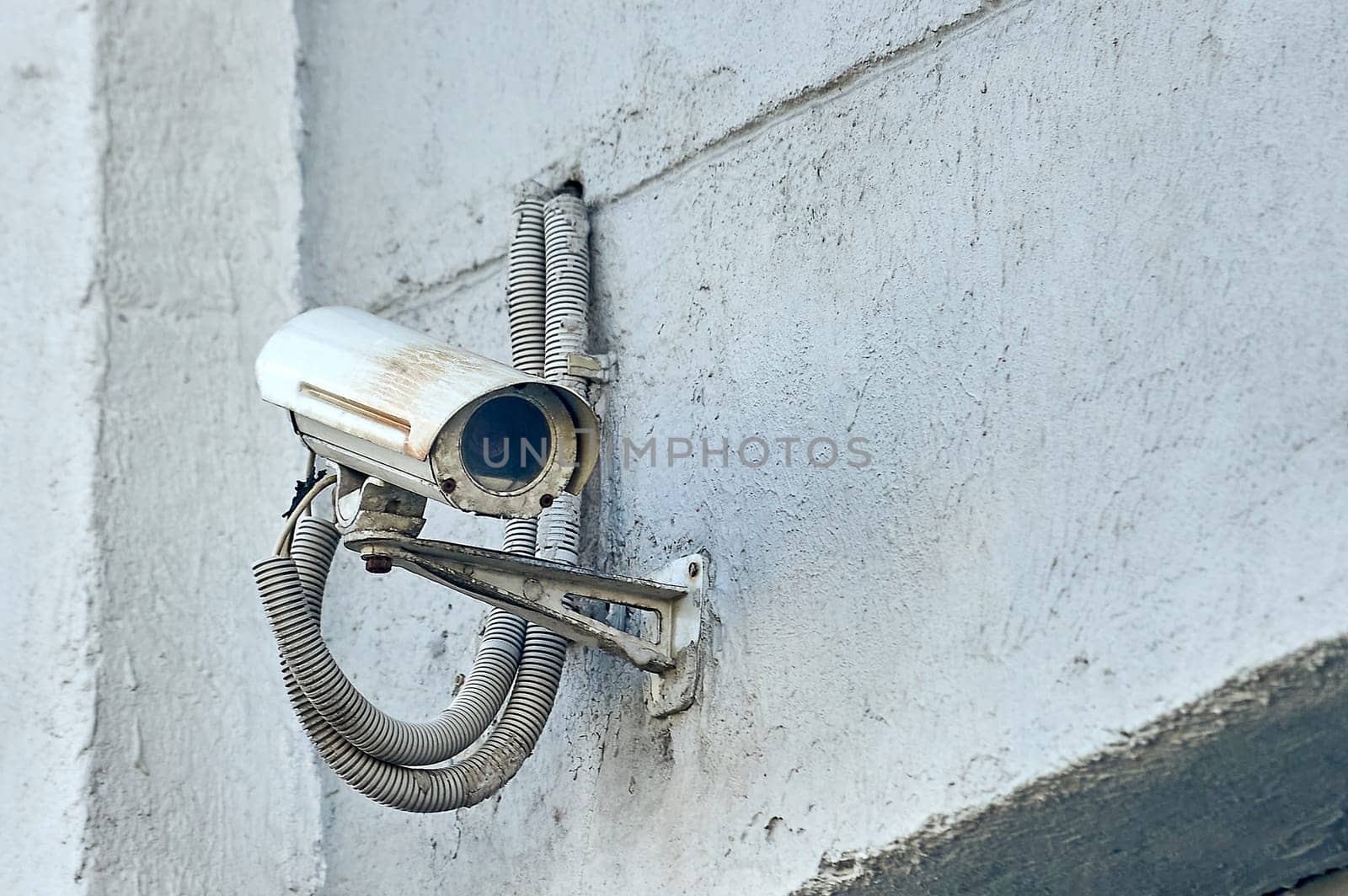 A security camera is hanging on a concrete post. High quality photo