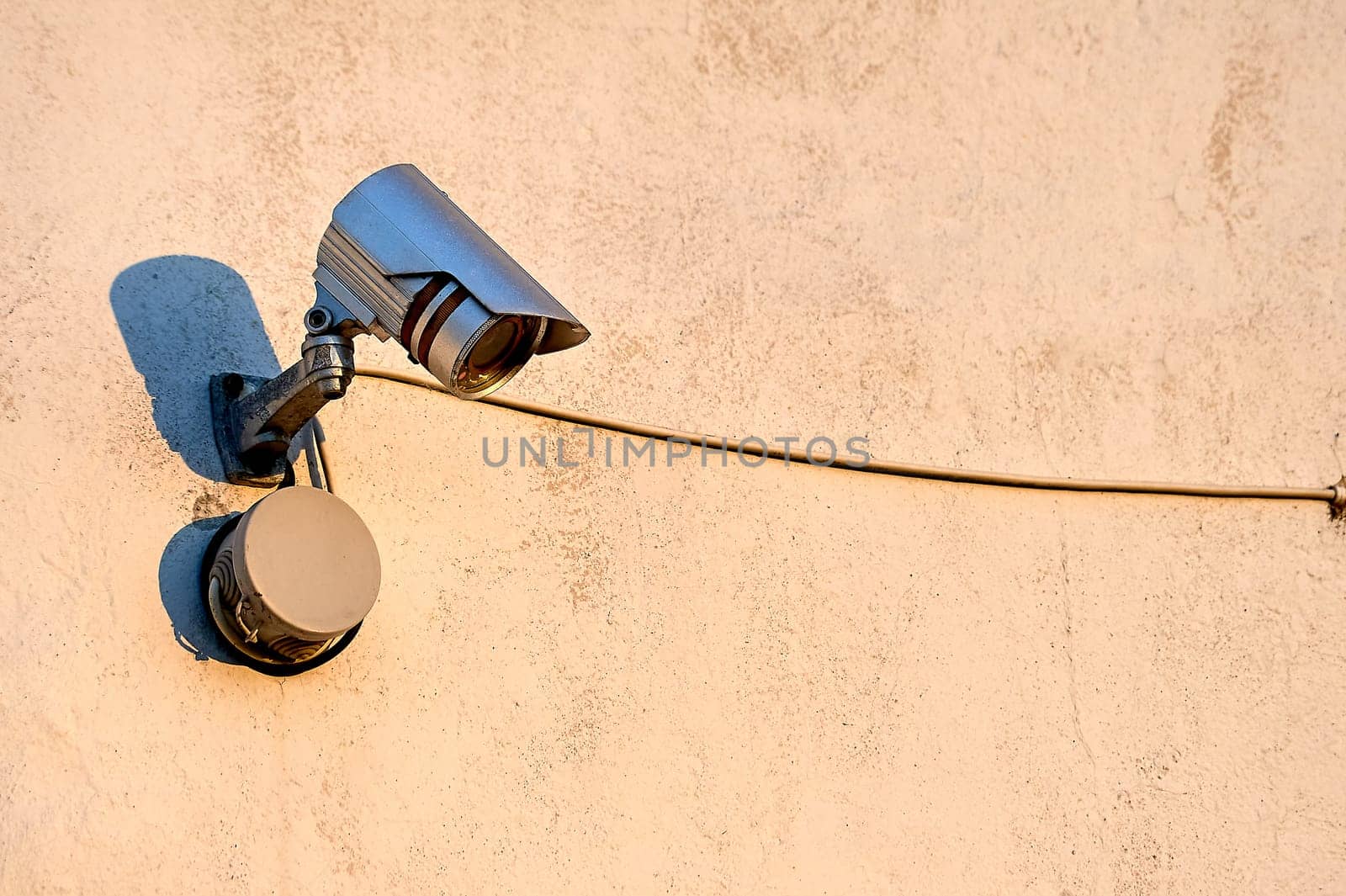 A surveillance camera is hanging on the wall of the house. High quality photo