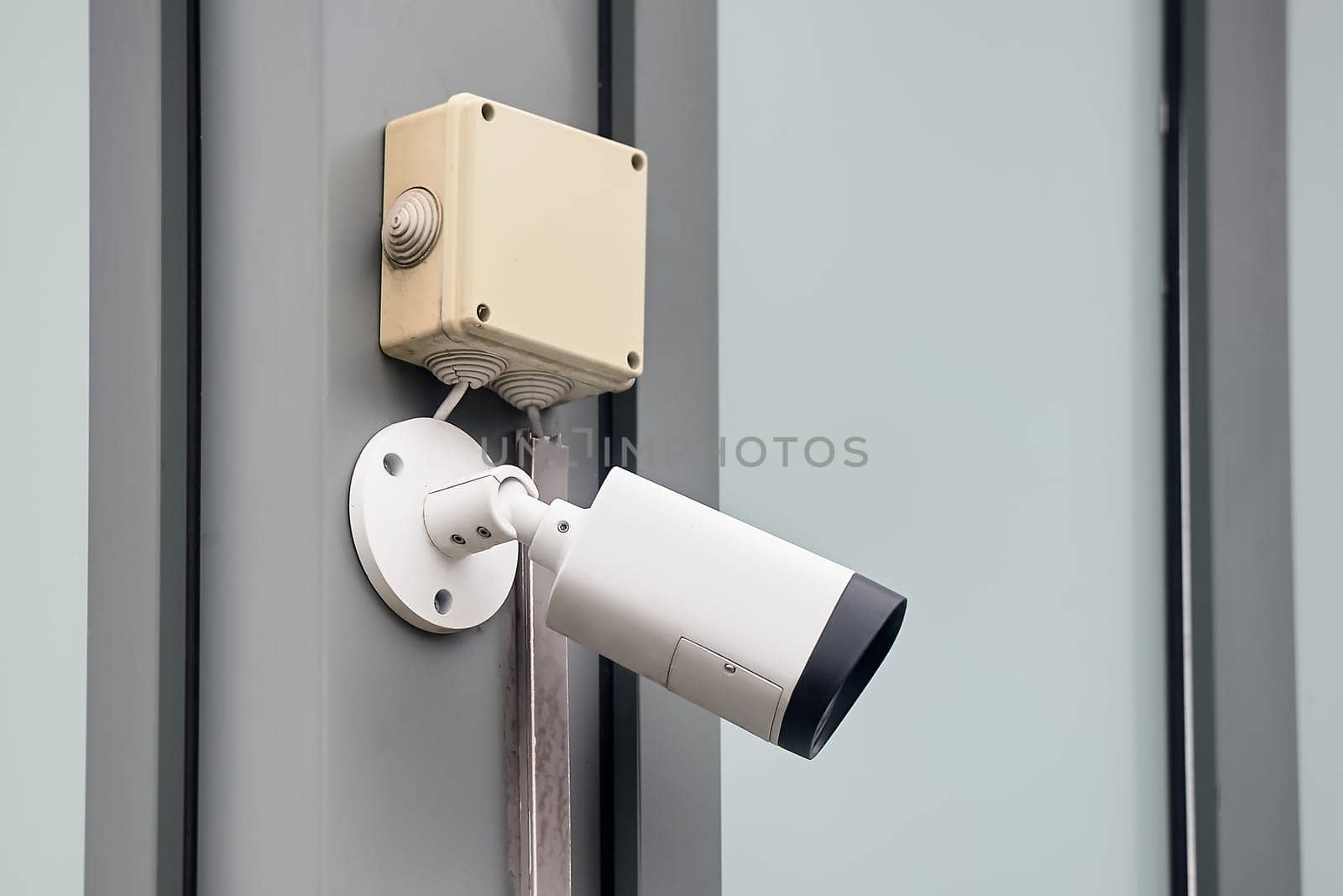 A video surveillance camera hangs on a metal profile. High quality photo