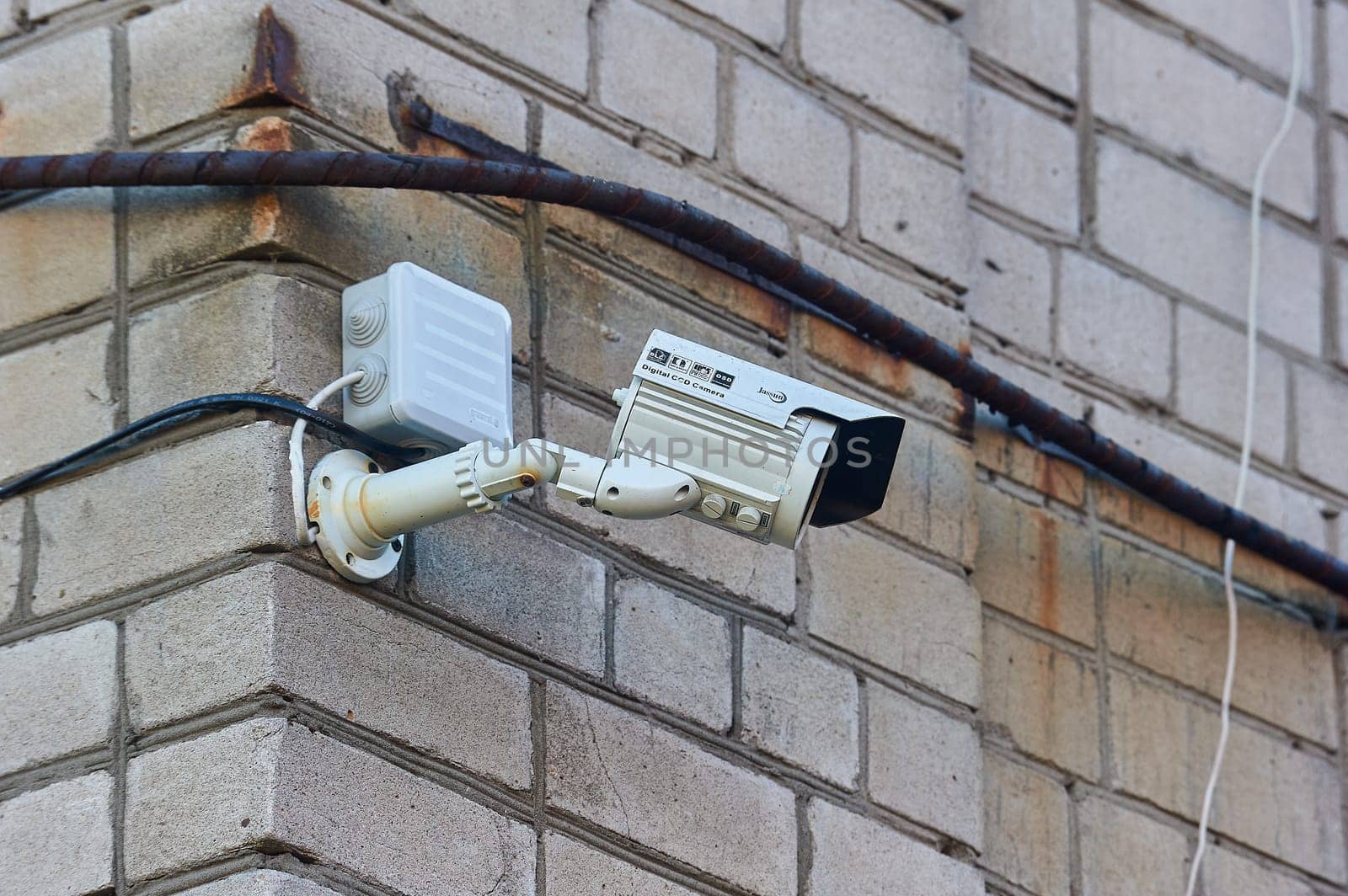 A surveillance camera is hanging on a brick wall. High quality photo
