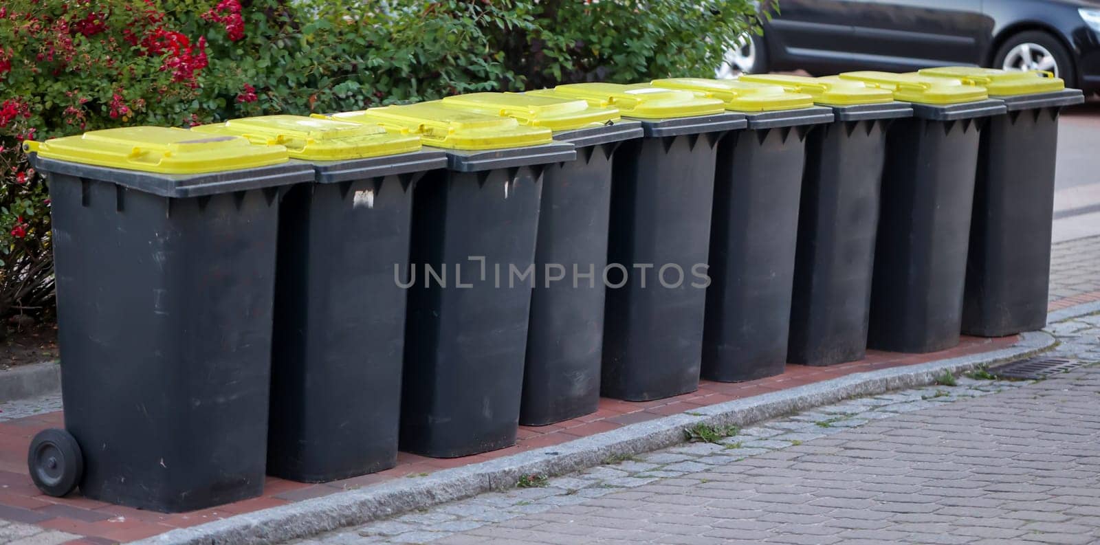 Several tons, yellow bins for plastic waste on a street.