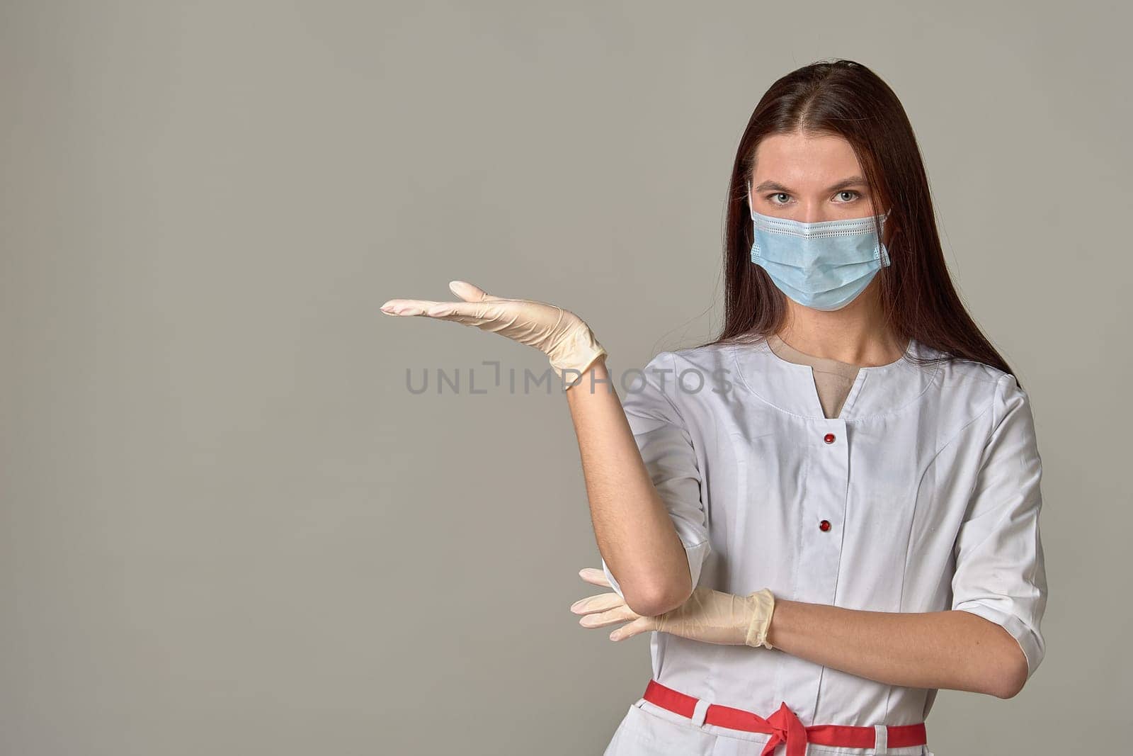 A female doctor in a medical mask points to an empty place, copy space. High quality photo