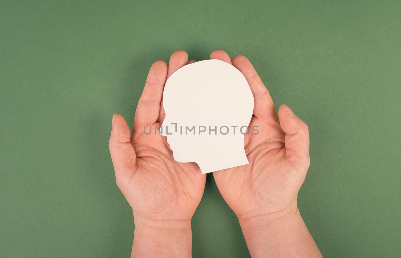 Holding a paper cut out head in the palms, symbolic for brainstorming, having an idea, new concepts, copy space for text