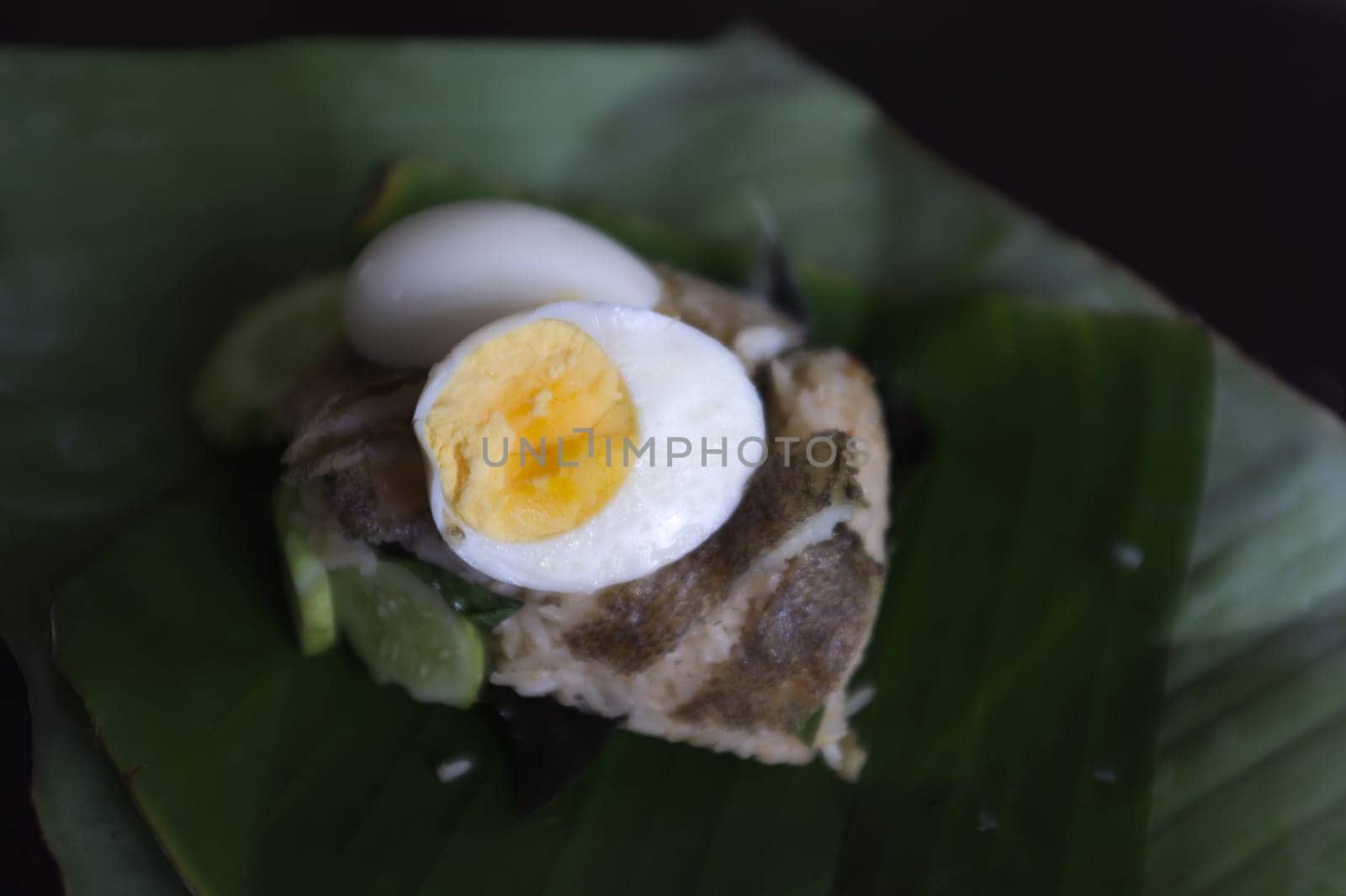 Crispy Gourami Fish and herb fried rice with boil egg on banana leaf