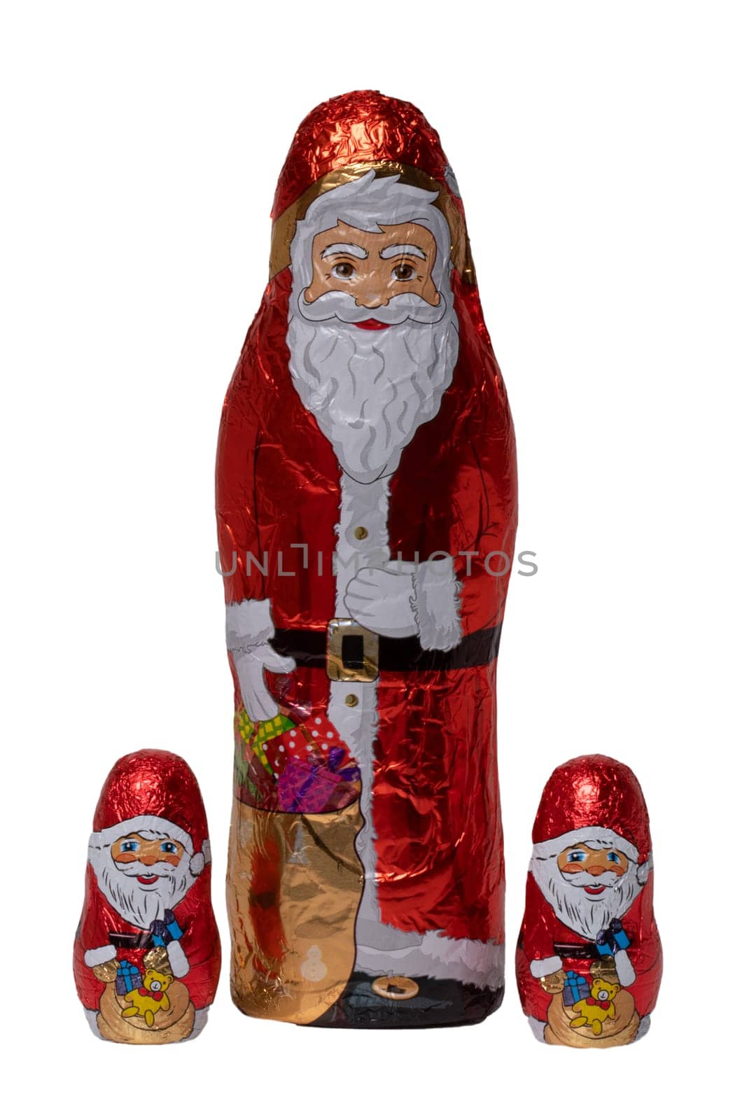 Chocolate Santa isolated. Close-up of three cheerful wrapped chocolate Santa Claus or the good Saint Nicolas figurine isolated on a white background. Macro photograph.
