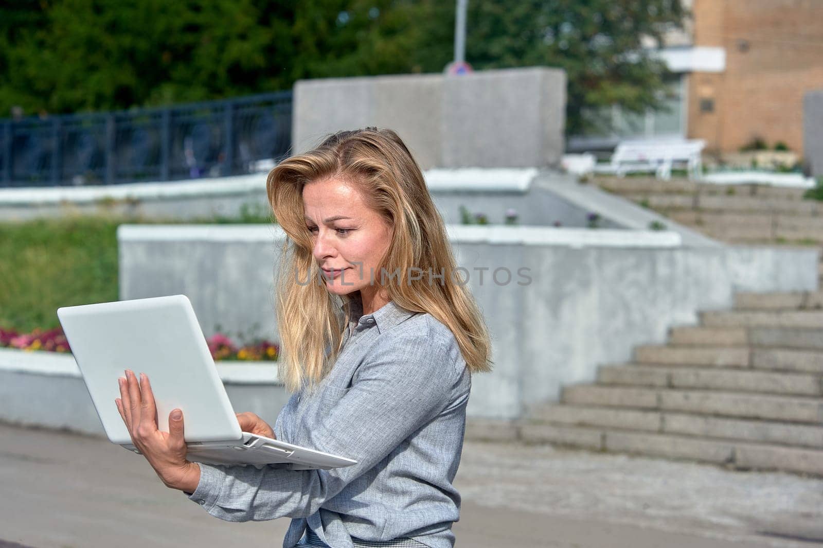 A woman with a laptop sits on a wooden platform, works online. High quality photo