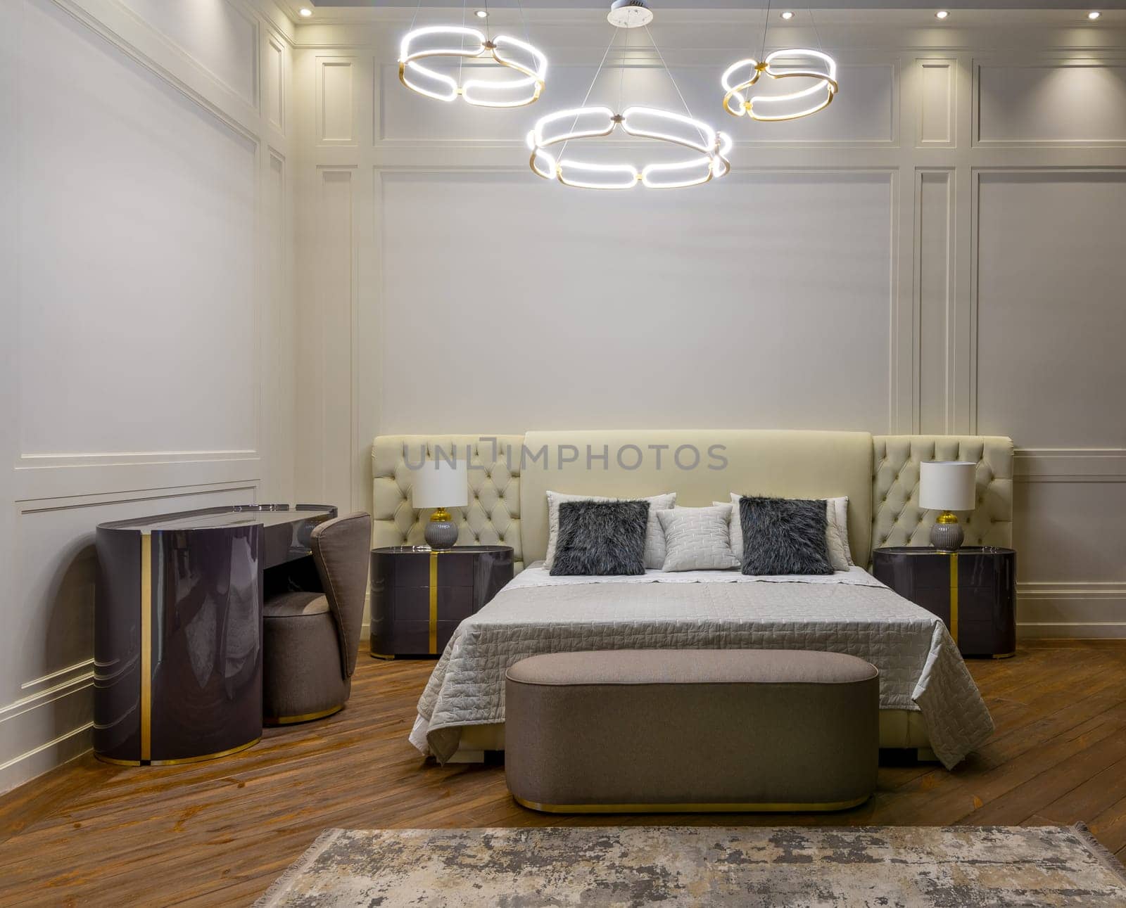 Interior of modern room with comfortable bed and bedside tables with lamps under ceiling with creative chandeliers