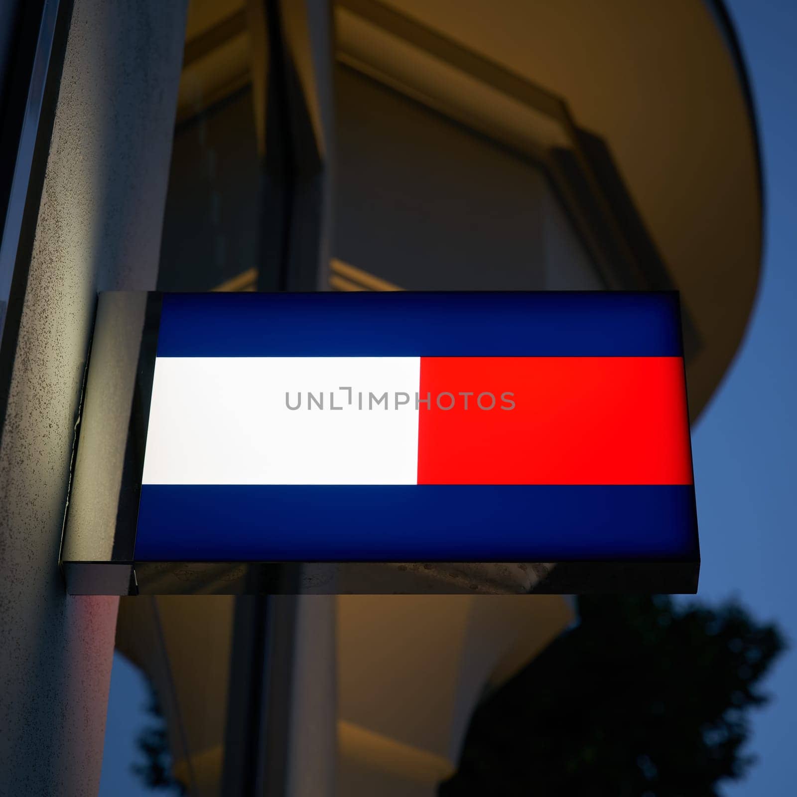 Neon light with the logo of fashion designer Tommy Hilfiger in a shopping street in Berlin in the evening