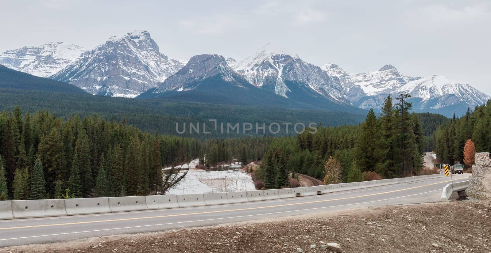 Scenery winter view of Nicholas Morant's Curve on Canadian Pacific Railway and Bow River with snow-covered Three Sisters Rocky Mountains background in Banff National Park, Alberta, Canada