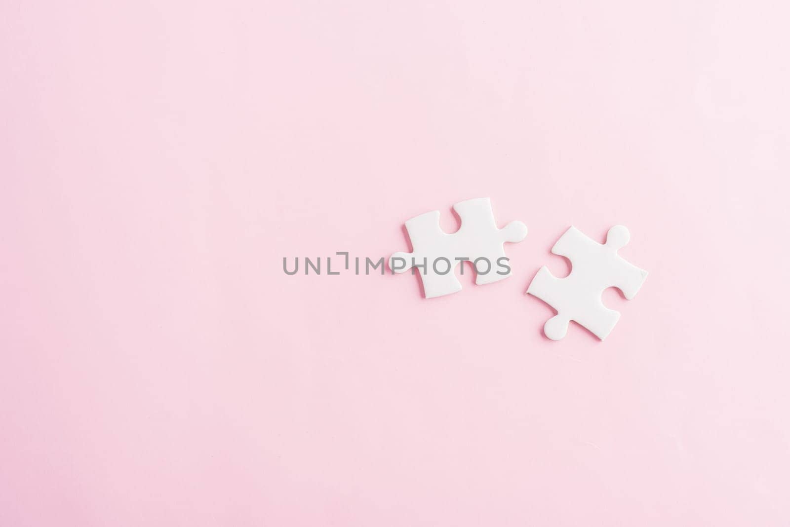 Top view flat lay of two paper plain white jigsaw puzzle game last pieces for solve, studio shot on a pink background, quiz calculation concept