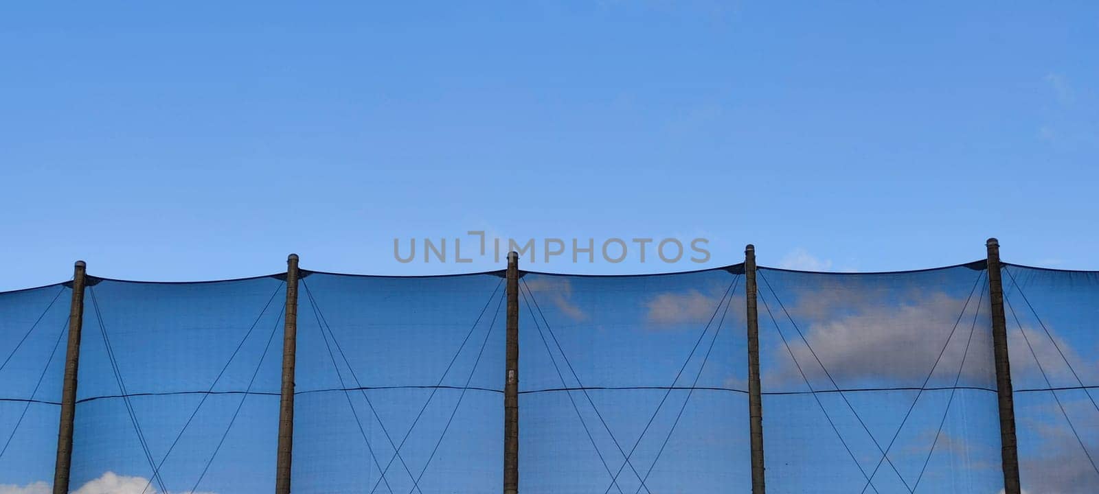 The net against blue sky. Beautiful cirrus clouds. Beautiful cirrus clouds over the sports field