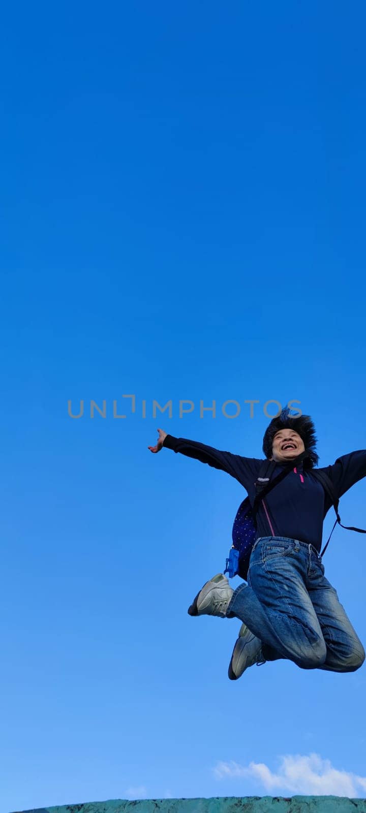 The girl in a jump. Young beautiful woman posing against blue sky bright sunny weather