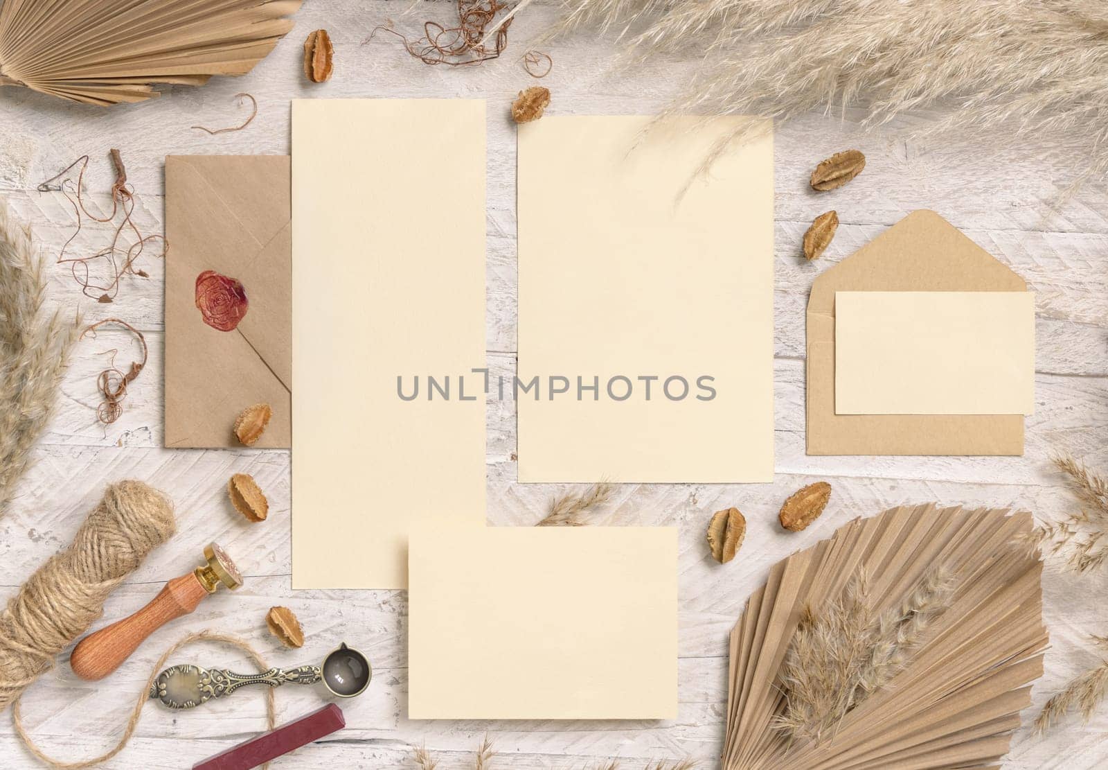 Wedding suite cards and envelope near dried plants, palm leaves and pampas grass top view. Boho scene with blank paper cards flat lay. Wedding set cards mockup, place for text