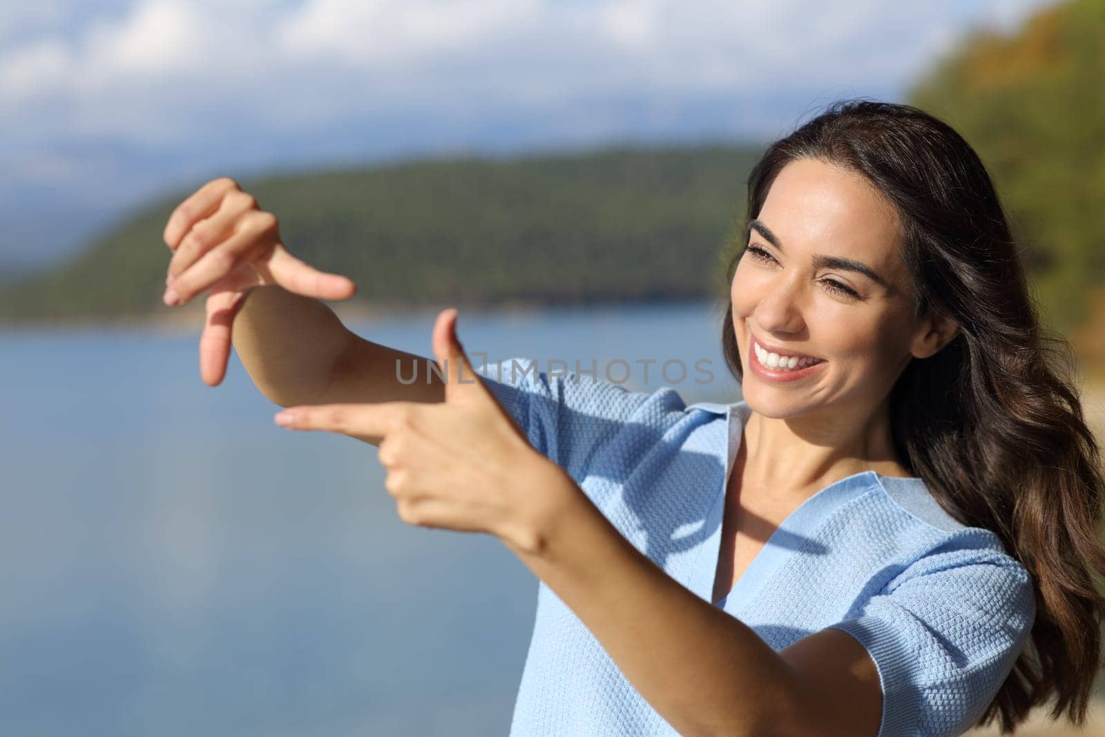 Happy woman framing with hands standing outdoors in nature