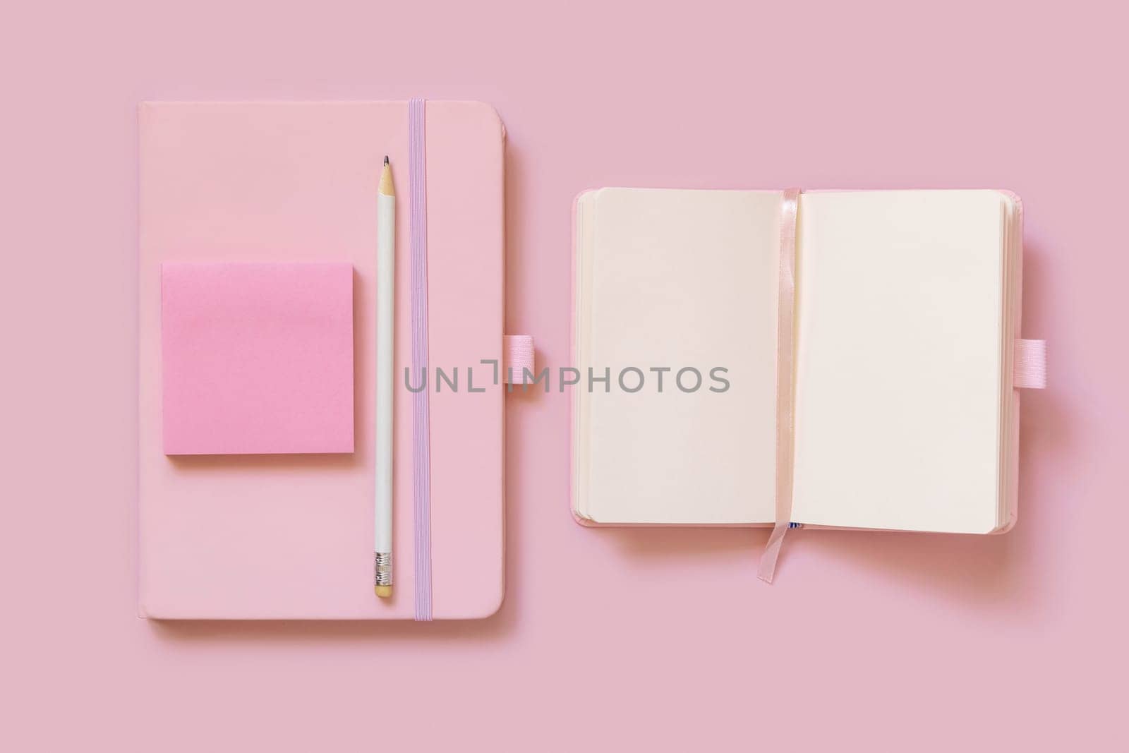 Pink notebooks, pencil and paper on light pink top view. Textbook mockup, planner cover with place fot text. Educational, business and organizing concept