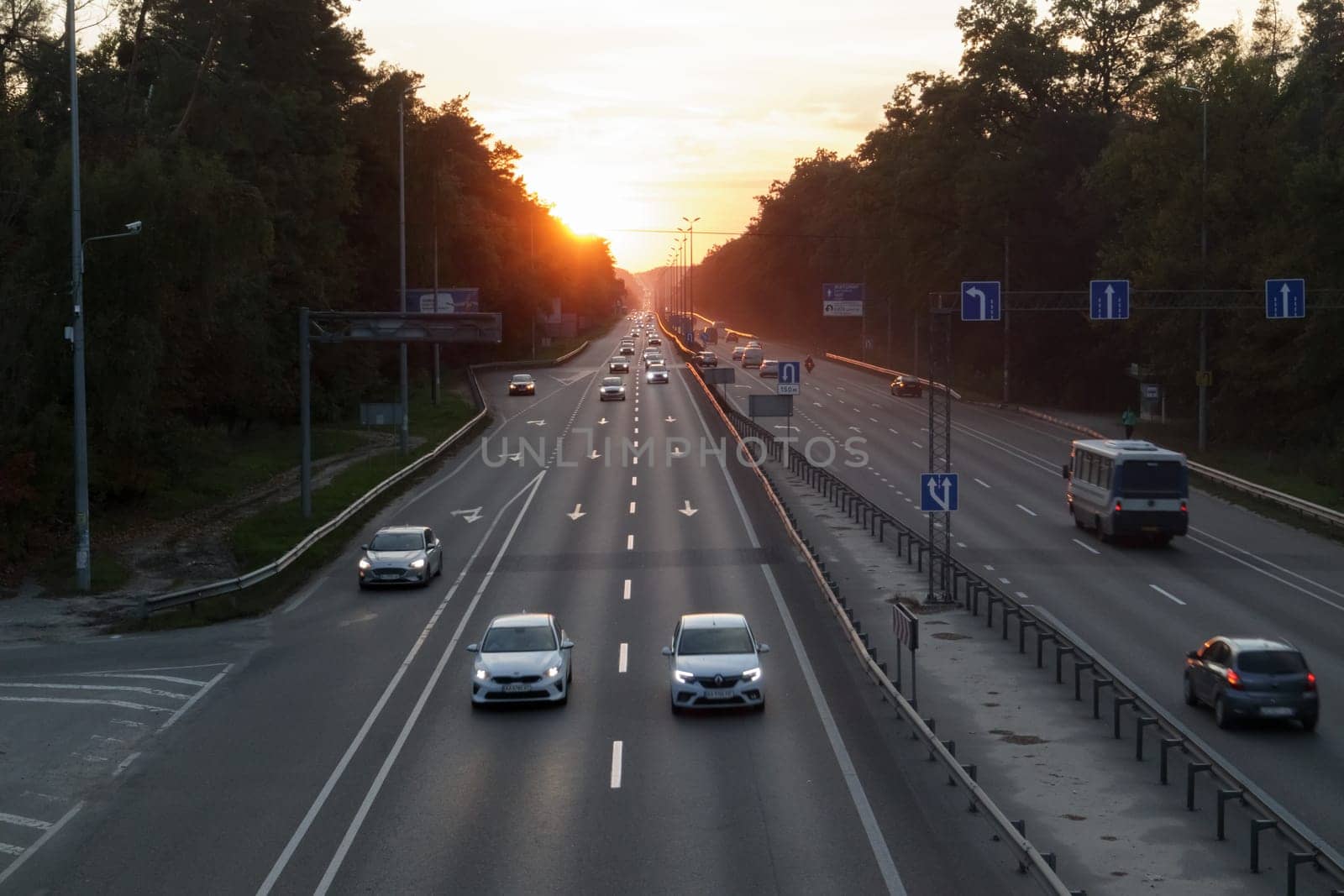 Moving cars on the motorway at sunset time. Highway traffic at sunset with cars. Busy traffic on the freeway, road top view