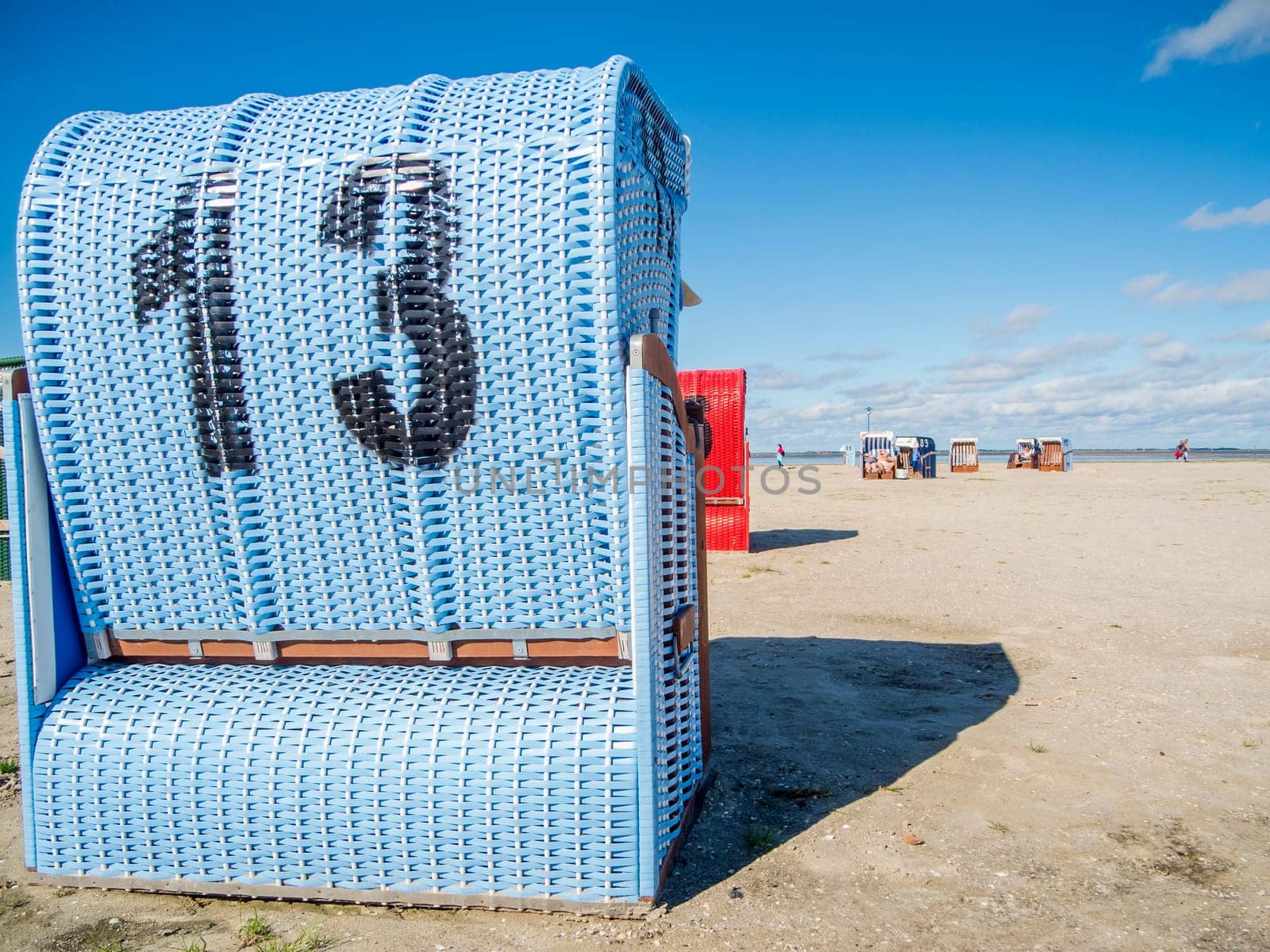Rear view of a light blue beach chair on the German North Sea coast in summer against a blue sky.
