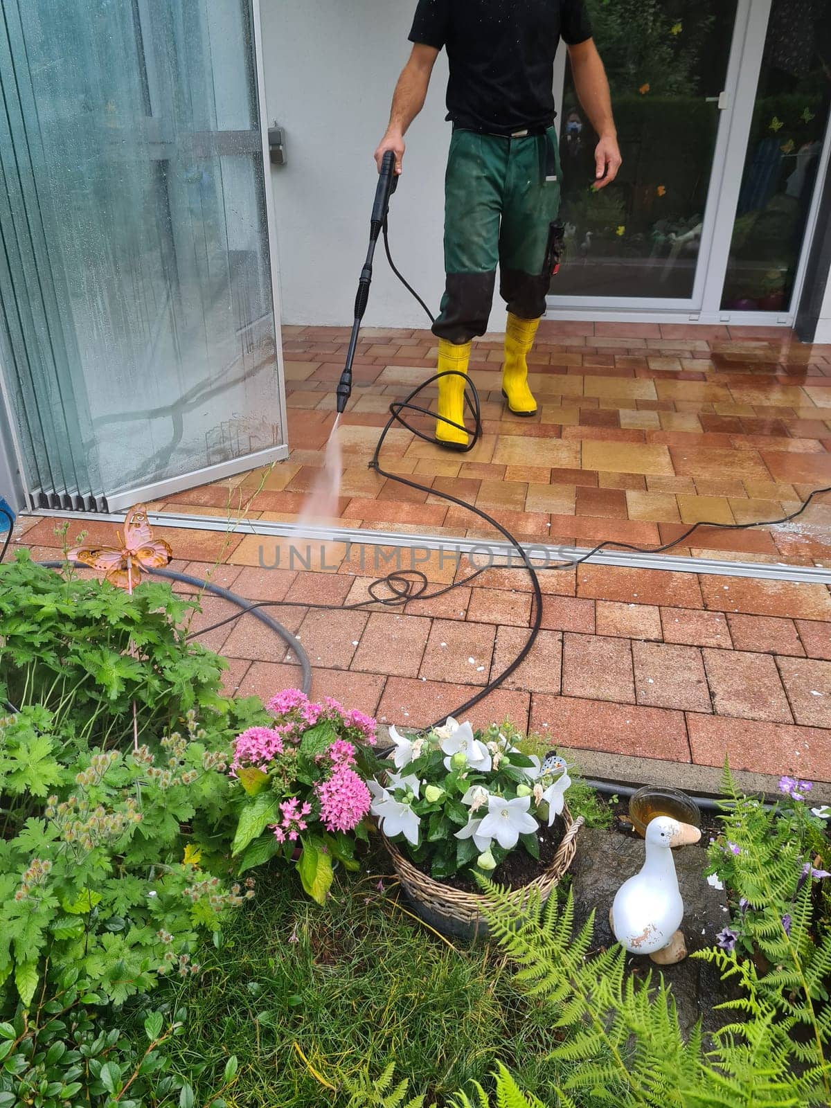 Man cleaning conservatory with a pressure washer - high pressure washer on patio glass surface