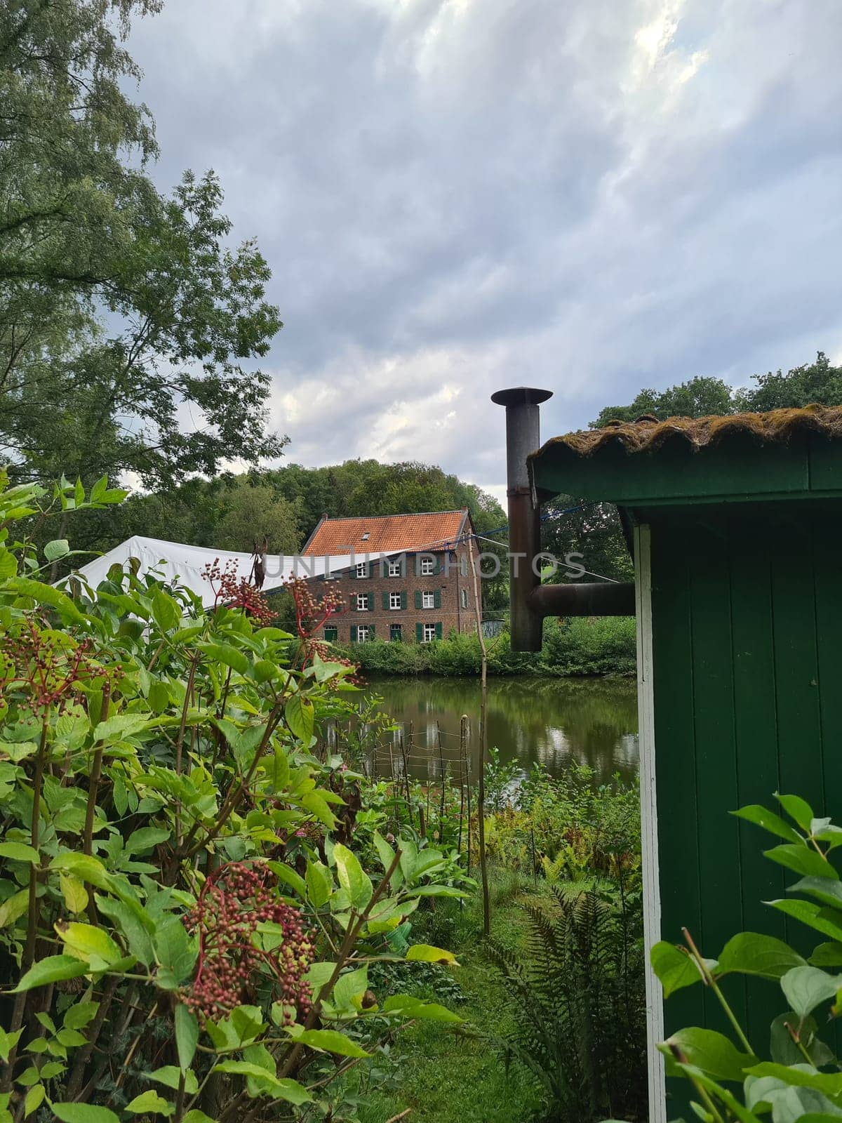 Red bricks house in countryside near the lake with mirror reflection in water