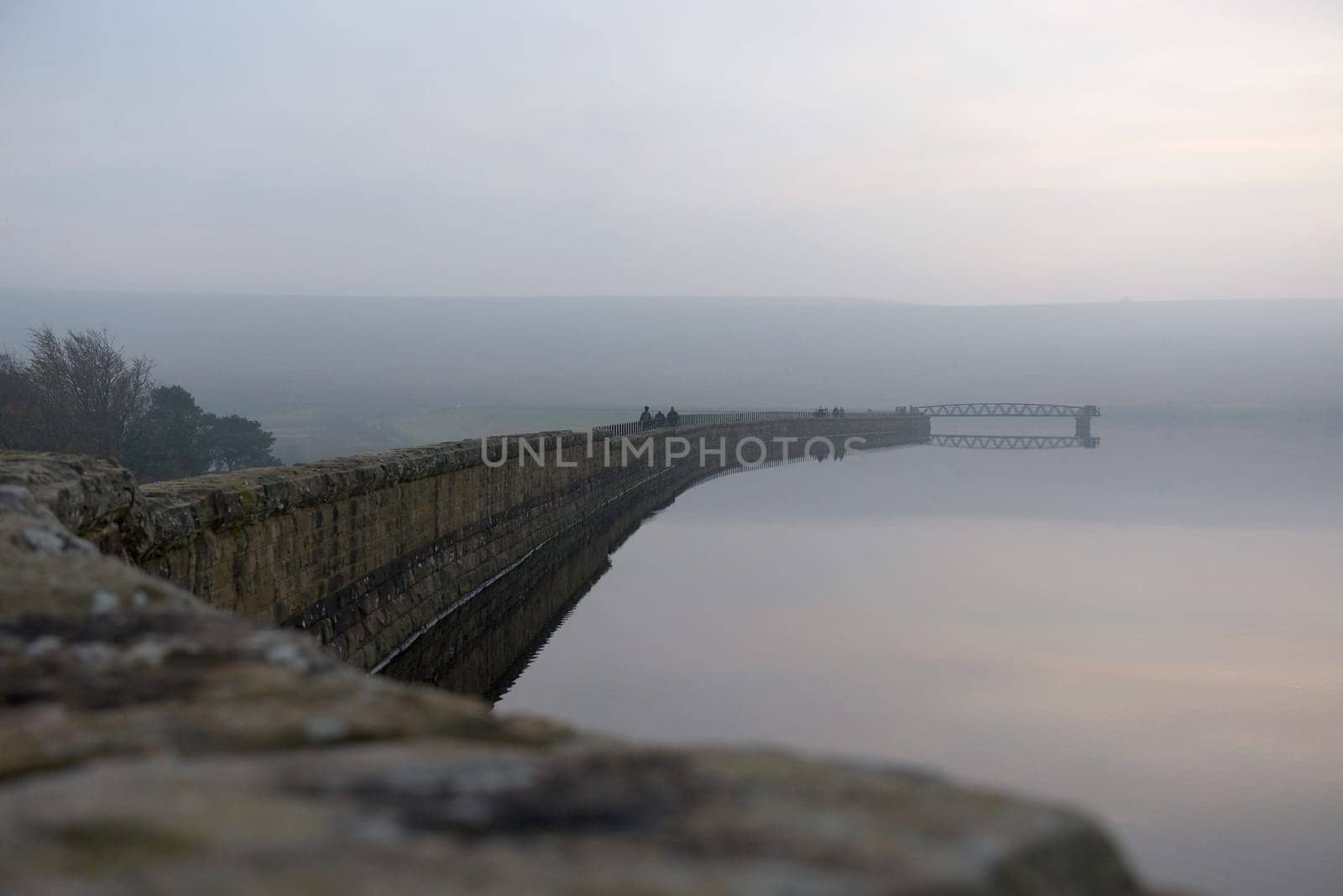 Sheffield, United Kingdom, 7th November, 2020: People enjoy a winters walk along redmires dam wall. Misty and foggy conditions surround the jetty