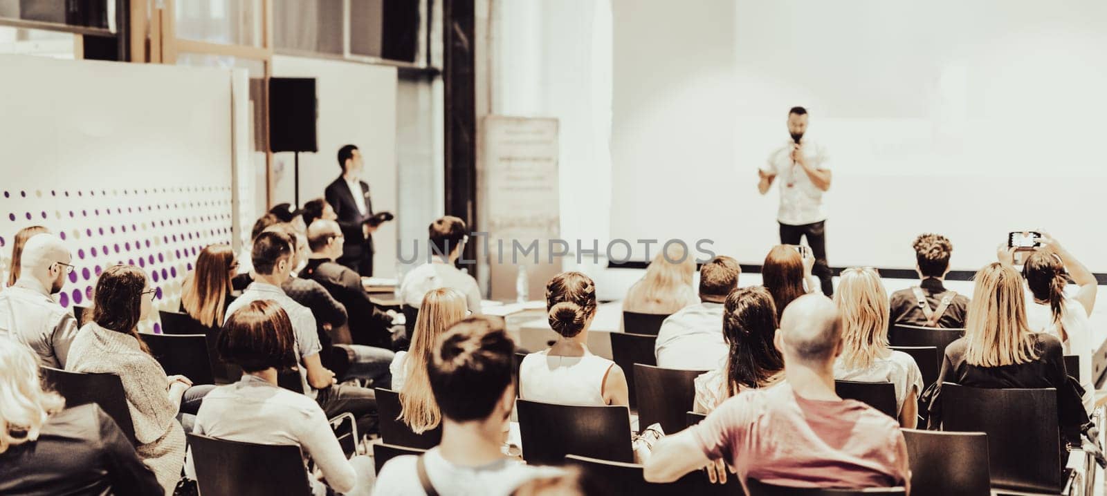 Speaker giving a talk in conference hall at business event. Rear view of unrecognizable people in audience at the conference hall. Business and entrepreneurship concept.
