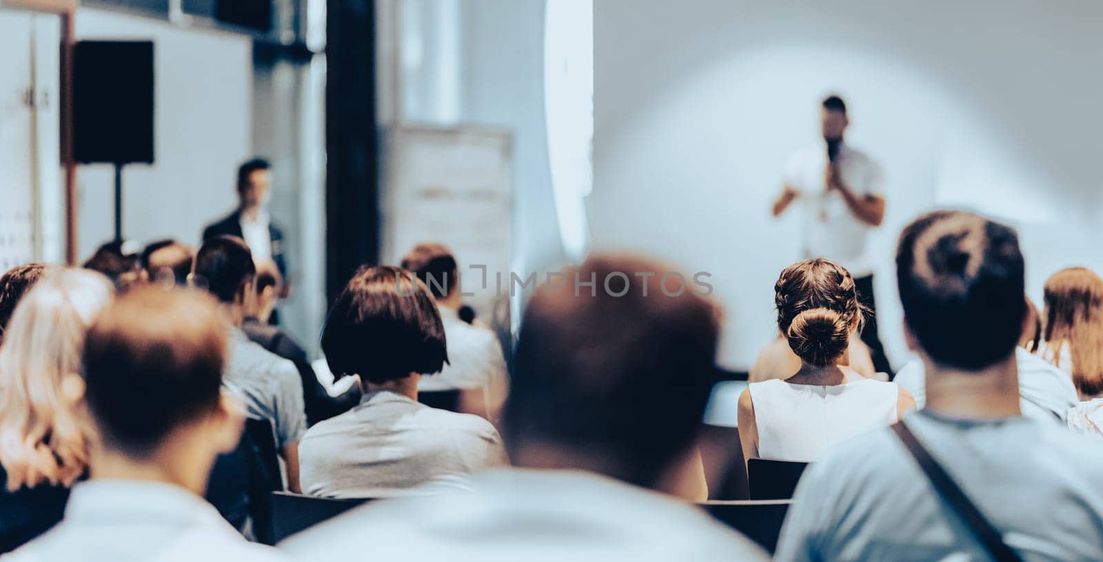 Speaker giving a talk in conference hall at business event. Rear view of unrecognizable people in audience at the conference hall. Business and entrepreneurship concept.