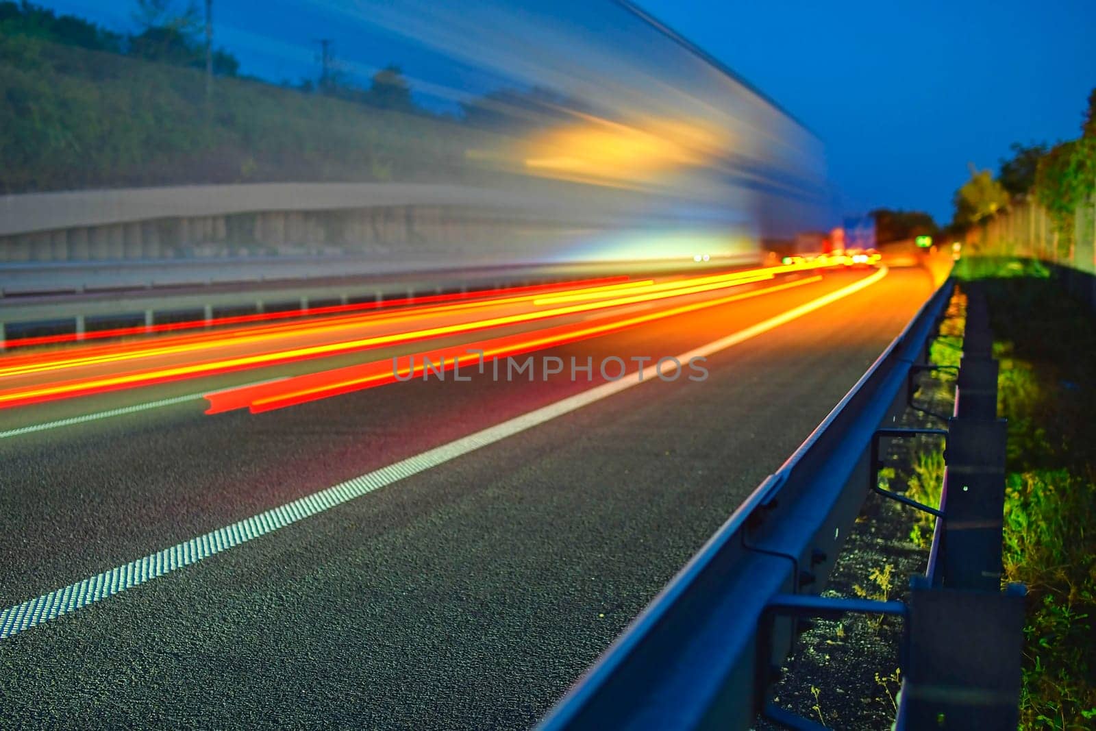 Evening shot of trucks doing transportation and logistics on a highway. Highway traffic - motion blurred truck on a highway-motorway- speedway at dusk.