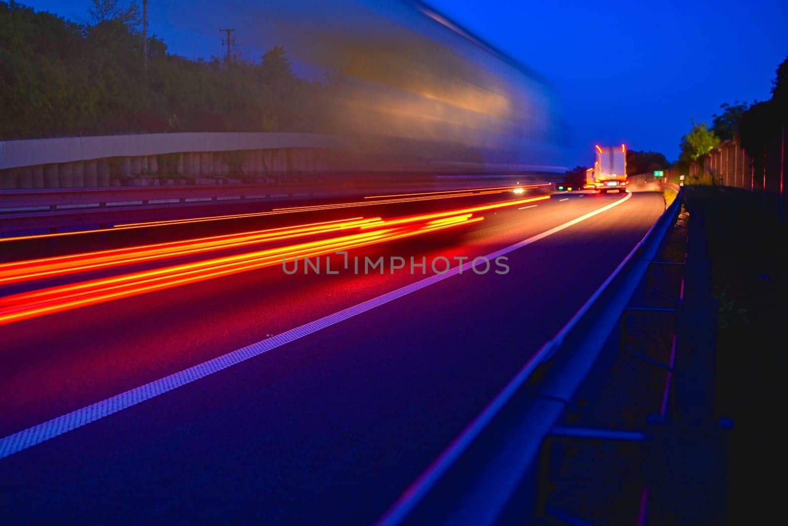 Evening shot of trucks doing transportation and logistics on a highway. Highway traffic - motion blurred truck on a highway-motorway- speedway at dusk.