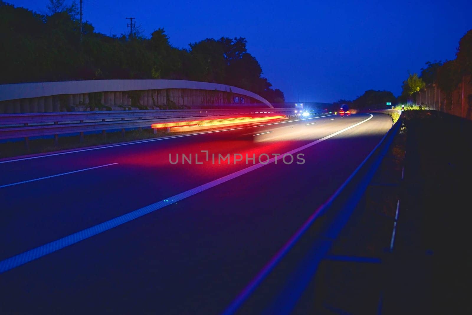 Evening shot of trucks doing transportation and logistics on a highway. Highway traffic - motion blurred truck on a highway-motorway- speedway at dusk.