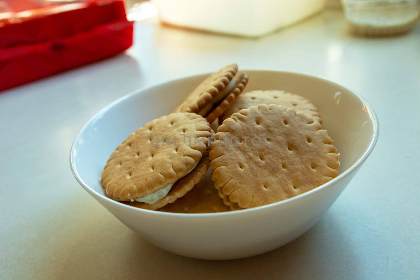 Cookies with cream in a white bowl on the table, sunny view