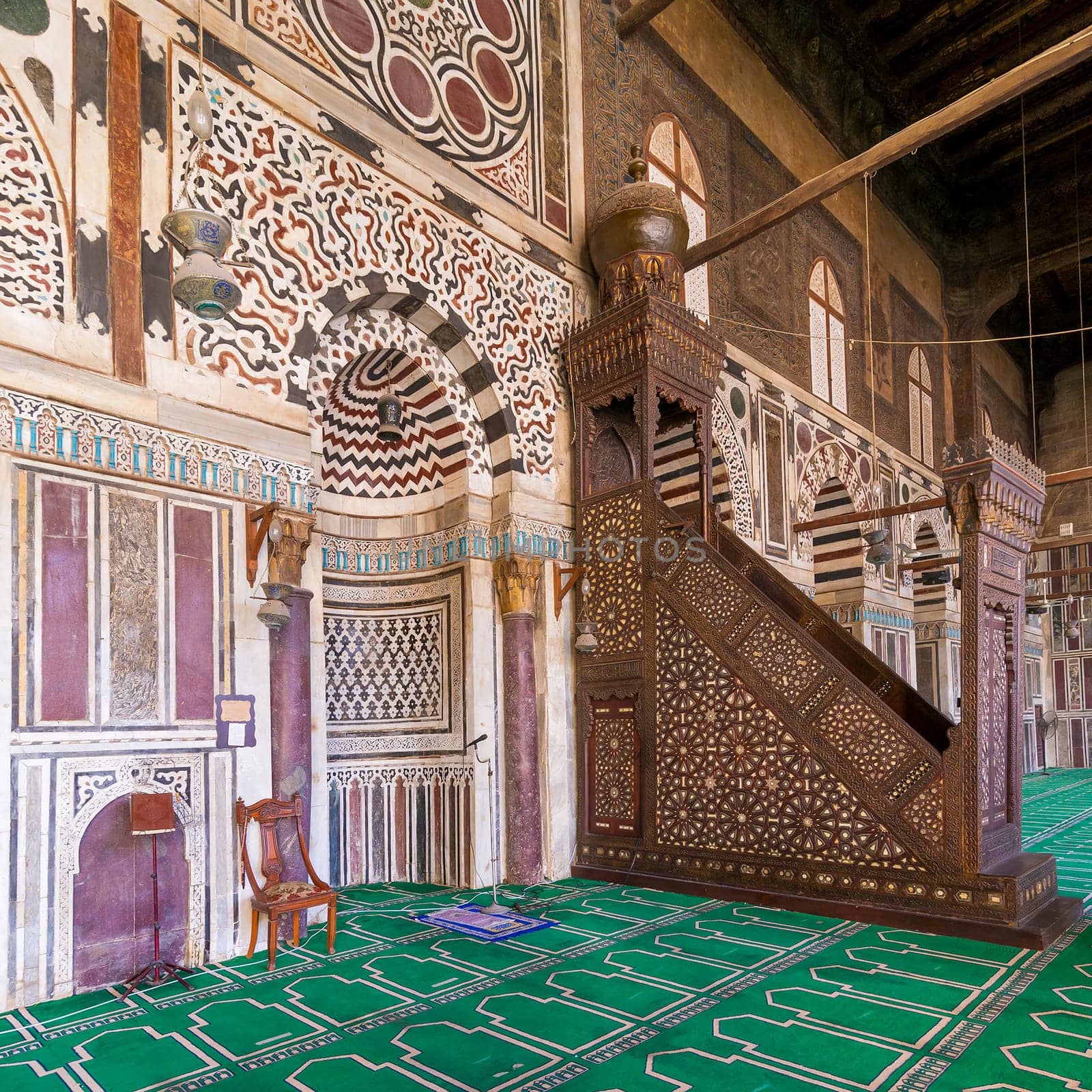 Colorful decorated marble wall with engraved Mihrab - niche - and wooden Minbar - Platform - at Mamluk era public historical mosque of Sultan al Muayyad, Old Cairo, Egypt
