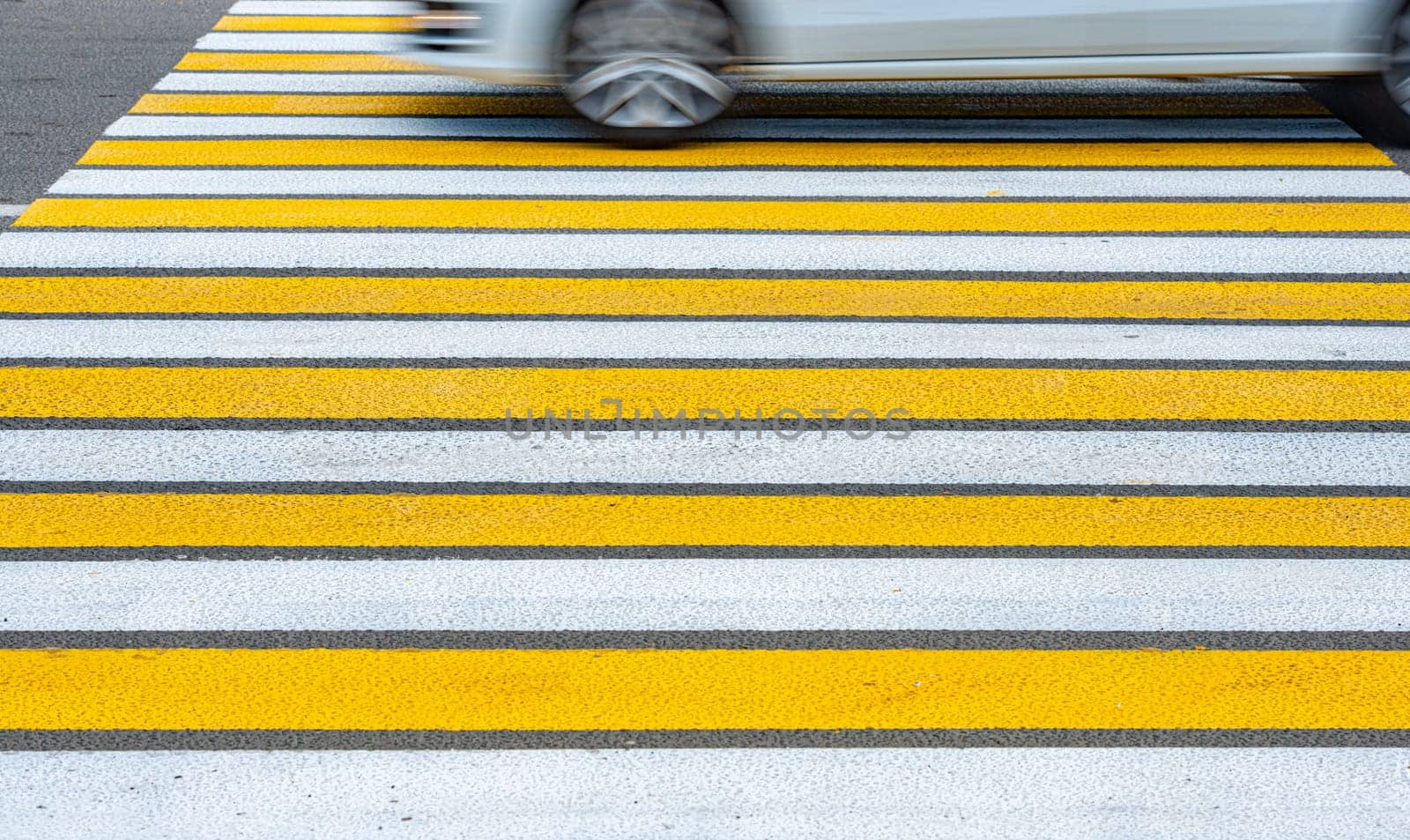 Yellow and white pedestrian crossing and car