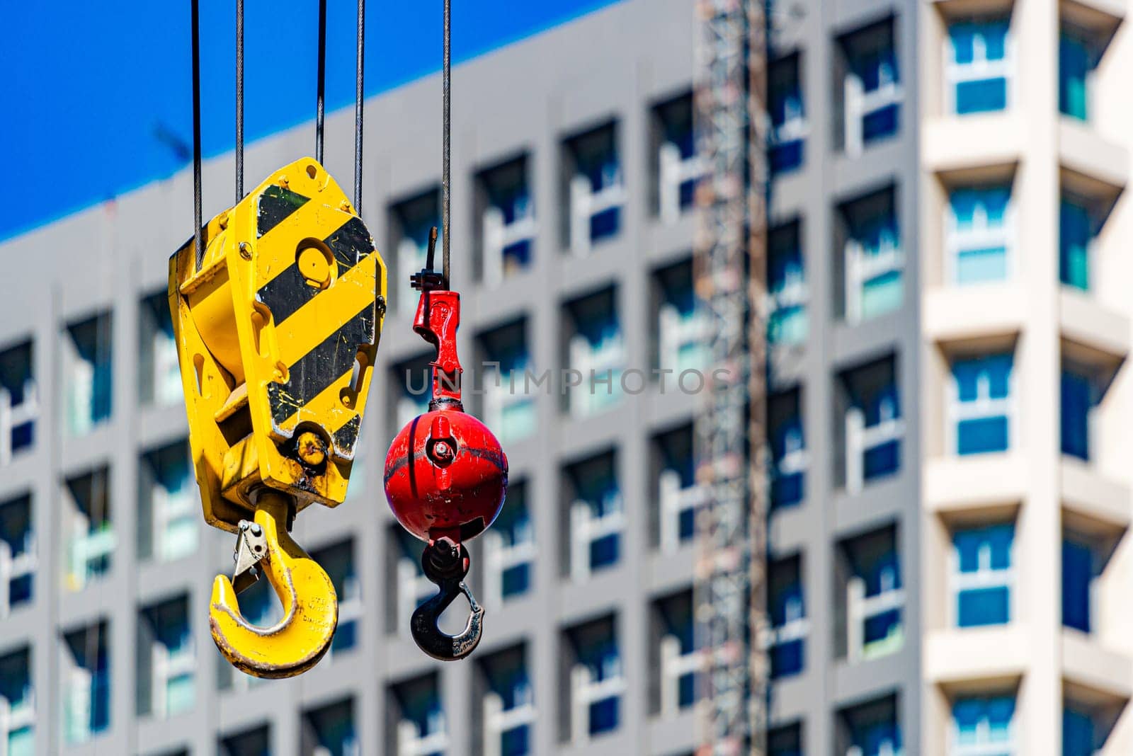 Hooks of crane on construction site with building and sky in background