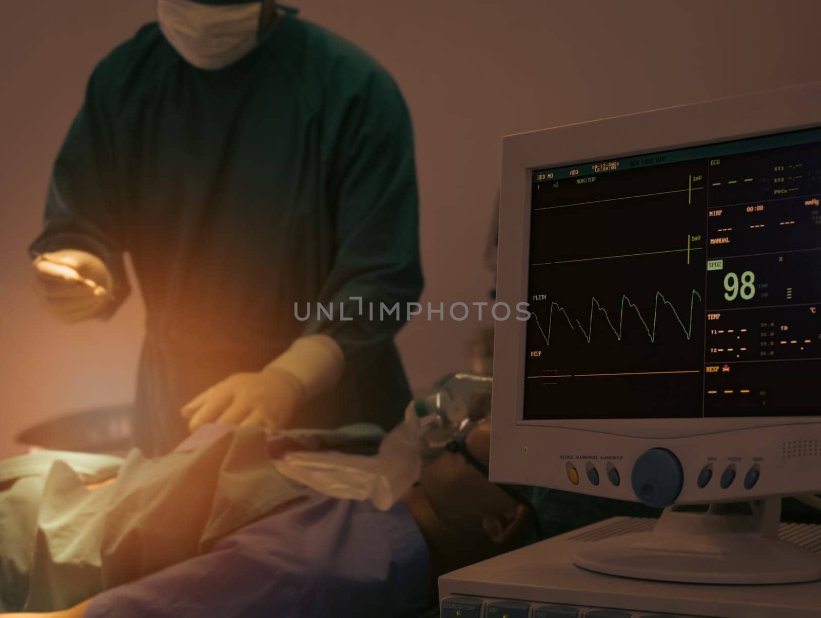 Monitoring of Electrocardiogram and saturation O2 of patient in hospital operating room with blur surgery in background