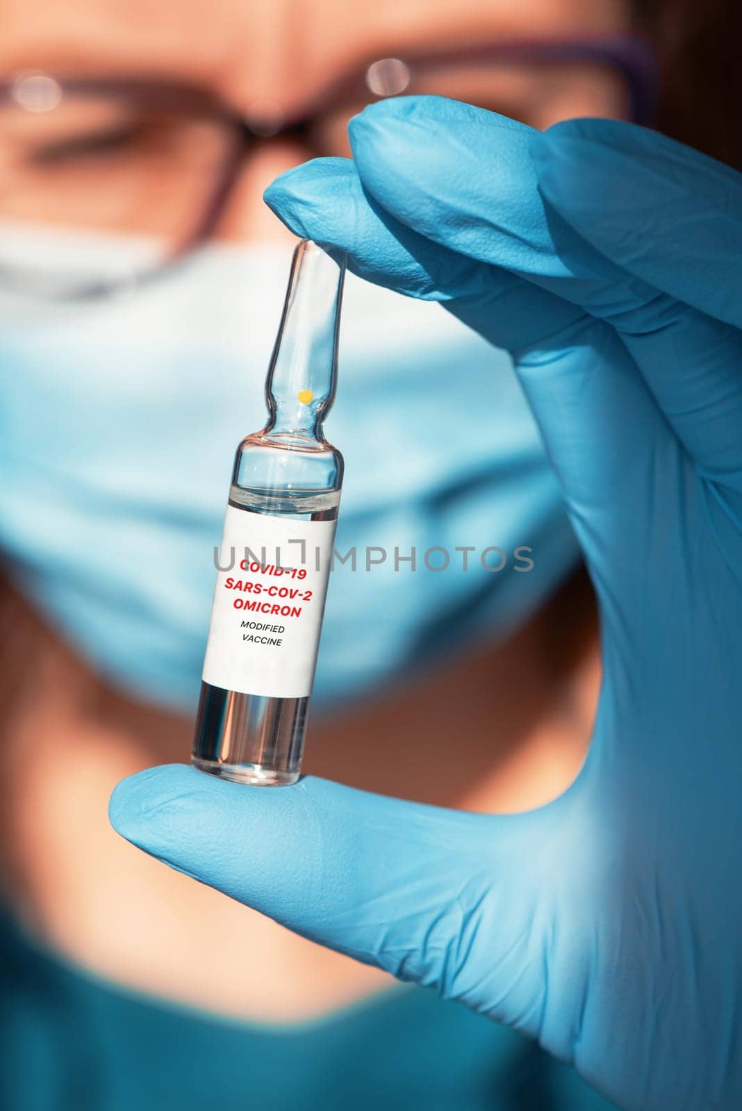 Coronavirus modified omicron vaccine in hand with blue protective gloves.