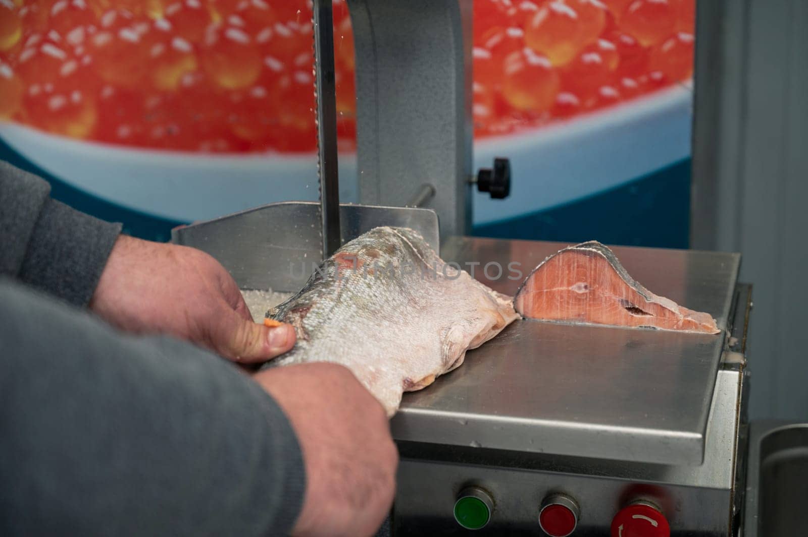 Service for cutting frozen salmon fish on a steak in a fish supermarket using professional equipment