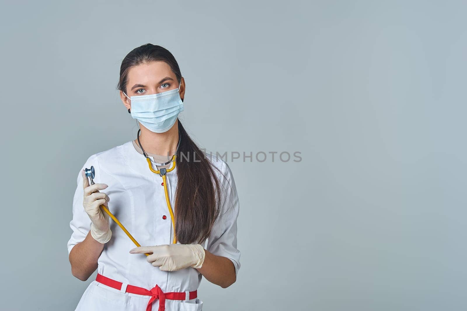 a doctor in a medical mask and white coat with a yellow stethoscope around his neck. High quality photo