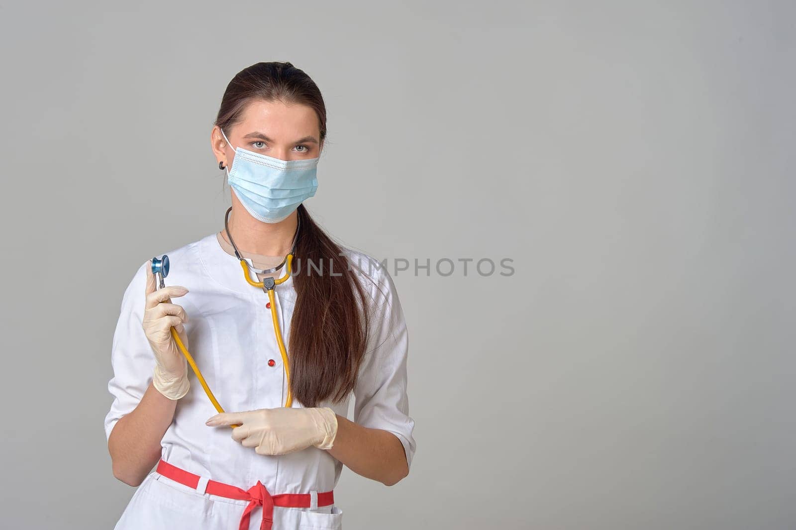 a doctor in a medical mask and white coat with a yellow stethoscope around his neck. High quality photo