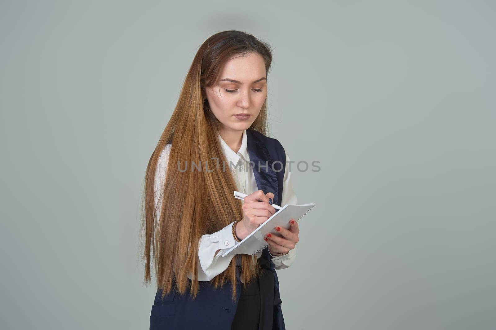 A young woman writes with a pen in a notebook on the background. High quality photo