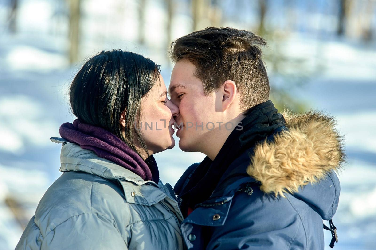 Young couple kissing outdoors in a winter park close up. High quality photo