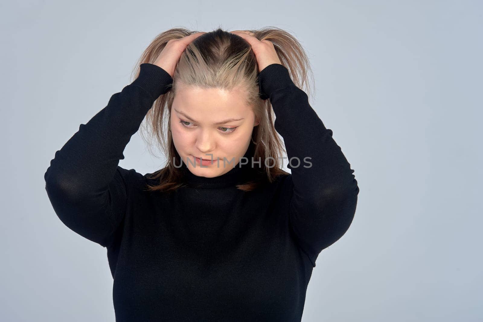 a woman holds her head, thinking, against an isolated background. High quality photo