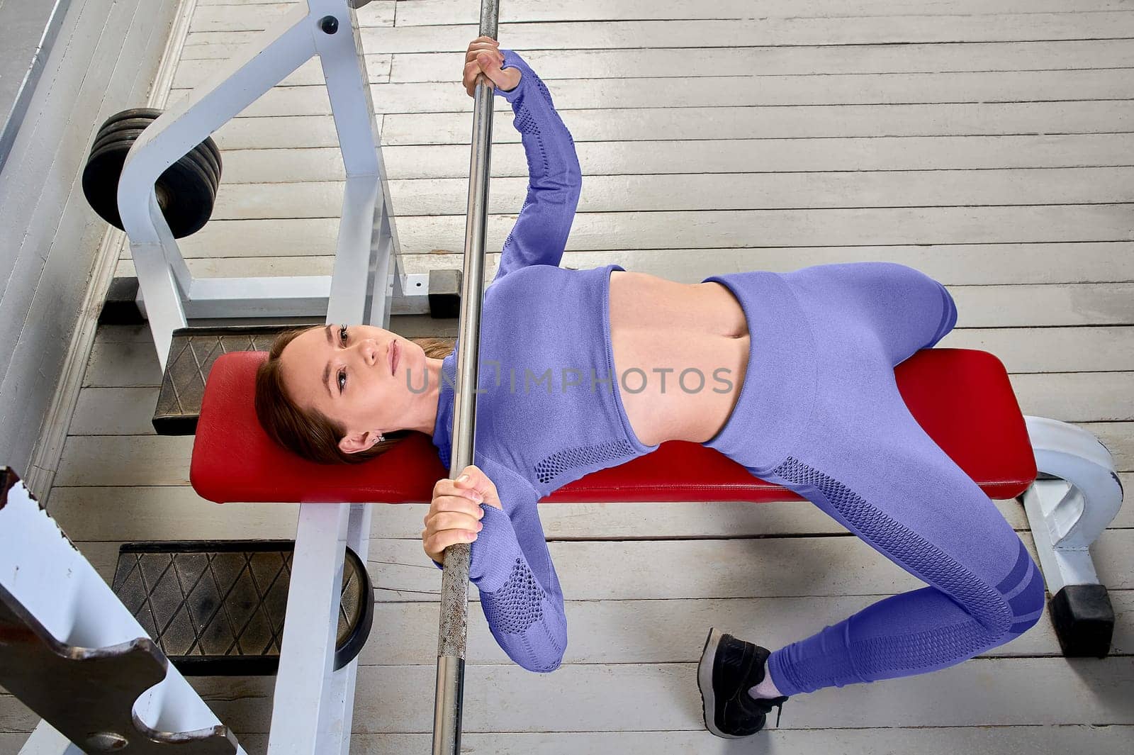 a young woman does a bench press lying on her back. High quality photo