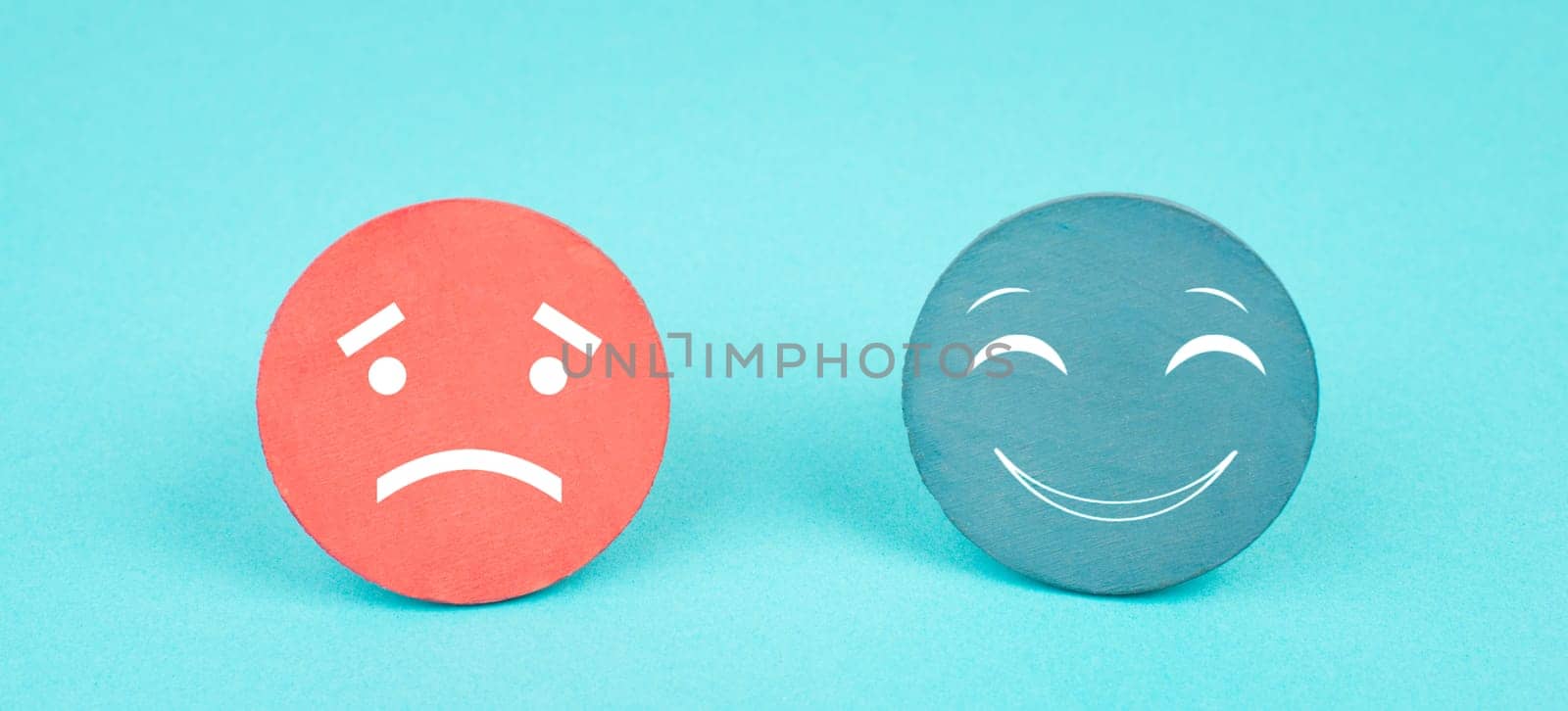 Two faces, smiling and sad in different colors on a blue background, copy space, rating, communication, customer feedback