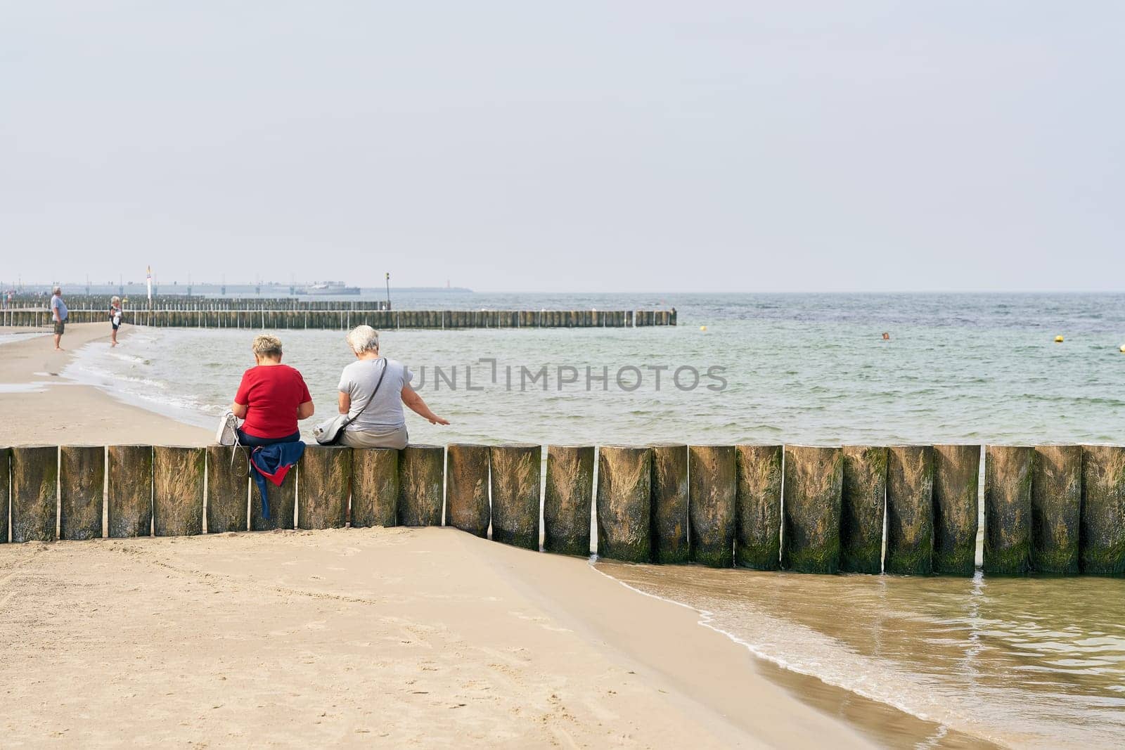 two old vacationers on a breakwater at the beach of Kolobrzeg at the Baltic Sea in Poland