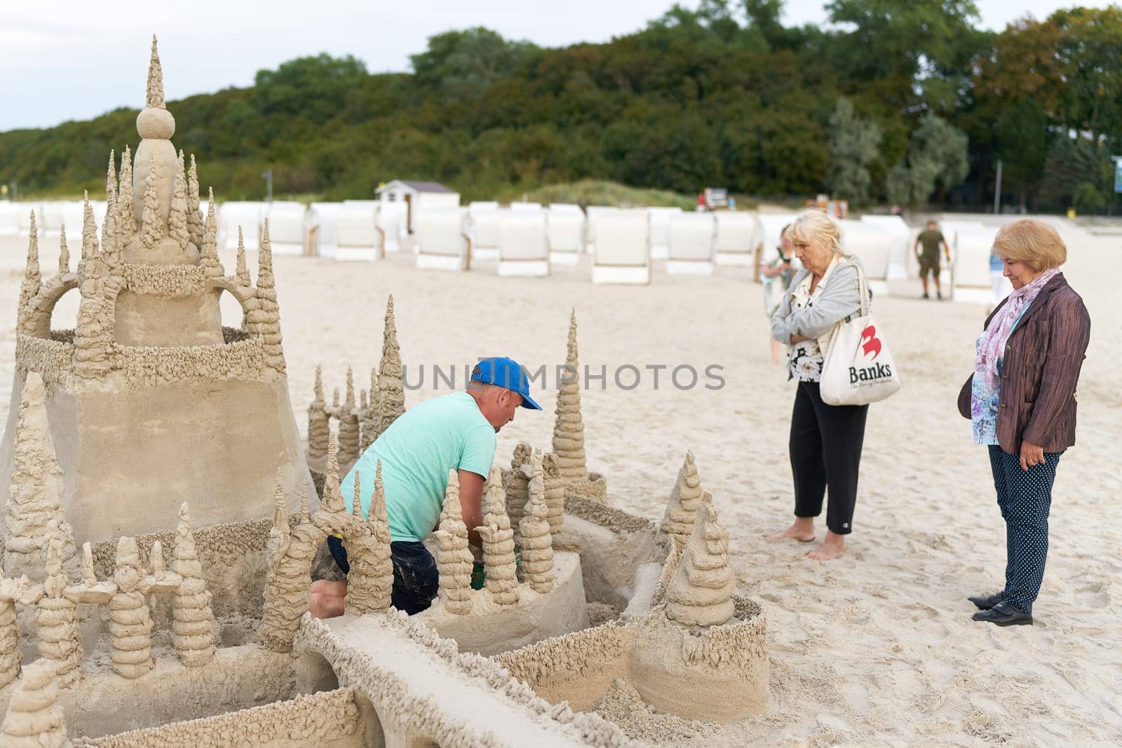 Holidaymakers admire a sandcastle on the beach of Kolobrzeg on the Polish coast of the Baltic Sea