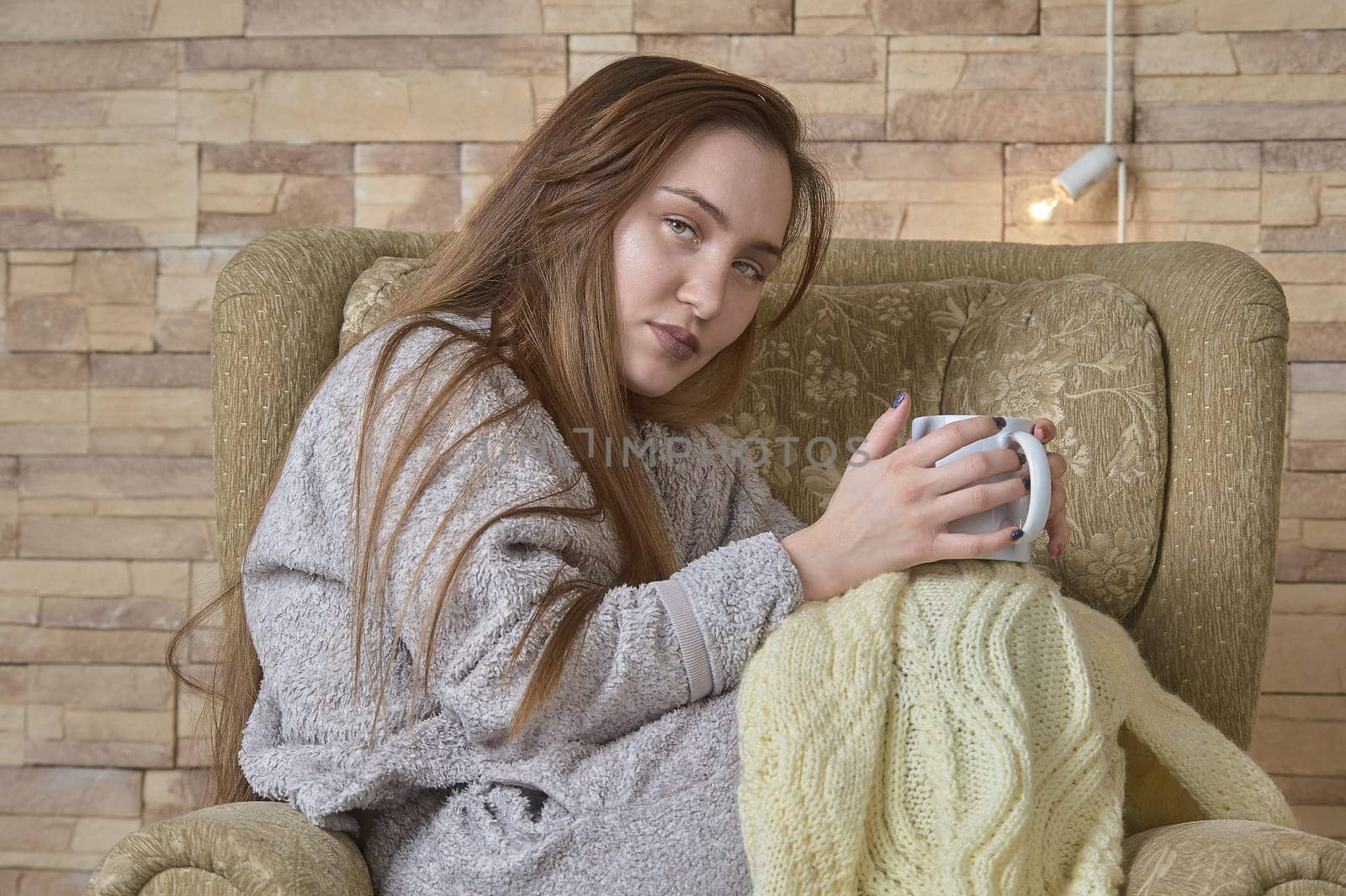 a girl in a chair with a cup of coffee covered with a blanket. High quality photo