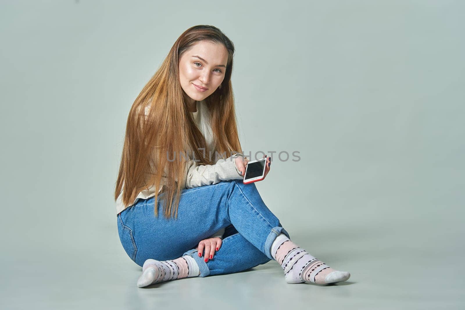 A girl sits in the background with a phone in her hands and smiles. High quality photo