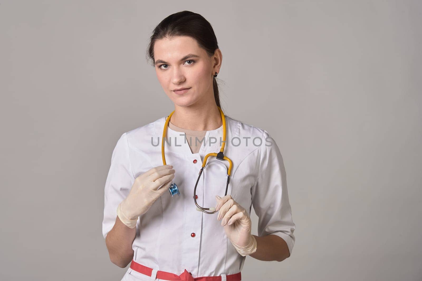 Female doctor with yellow stethoscope and gloves on background. High quality photo
